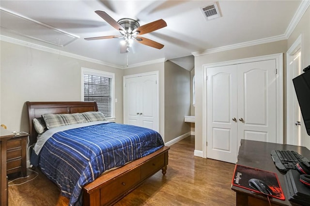 bedroom featuring visible vents, attic access, wood finished floors, and crown molding