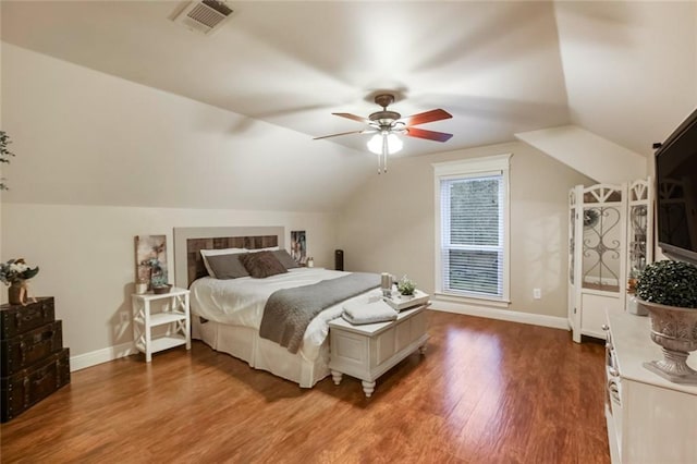 bedroom featuring baseboards, lofted ceiling, visible vents, and wood finished floors