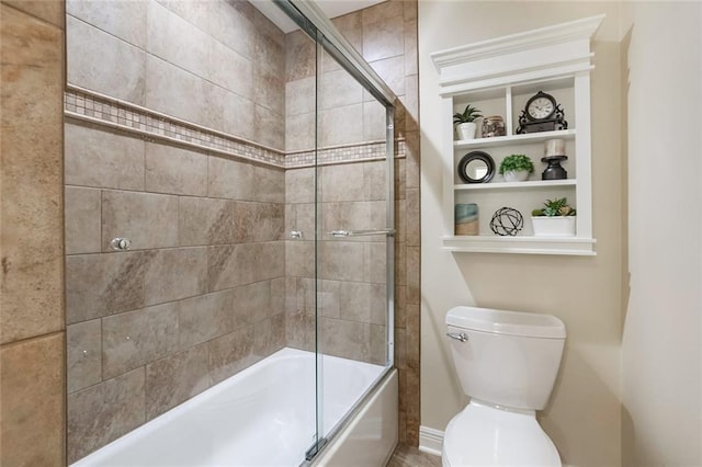 bathroom featuring built in features, toilet, and combined bath / shower with glass door