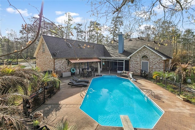 view of swimming pool with a fenced in pool, fence, a sunroom, a patio area, and a diving board