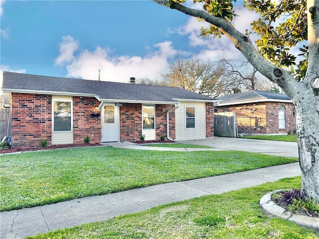 ranch-style house featuring brick siding, concrete driveway, a front yard, and fence