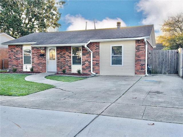 single story home featuring brick siding, a shingled roof, a front yard, and fence