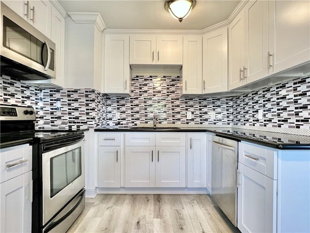 kitchen with dark countertops, backsplash, stainless steel appliances, and light wood-style floors