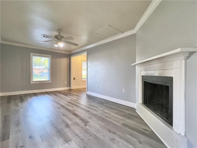 unfurnished living room featuring visible vents, ornamental molding, wood finished floors, baseboards, and attic access