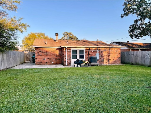 back of property with a patio, a fenced backyard, brick siding, and a lawn