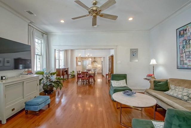 living area featuring visible vents, crown molding, light wood-type flooring, recessed lighting, and ceiling fan with notable chandelier