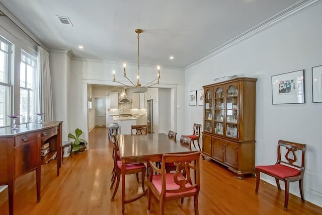 dining room with visible vents, crown molding, and light wood-type flooring