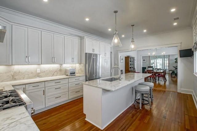 kitchen featuring light stone counters, dark wood-style floors, white cabinets, stainless steel appliances, and a sink