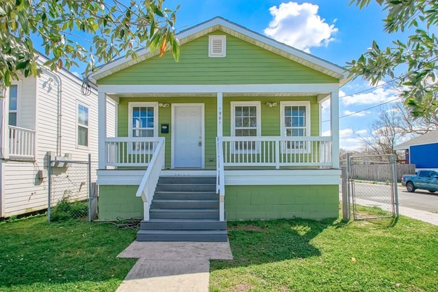 shotgun-style home featuring a porch, fence, a front lawn, and a gate