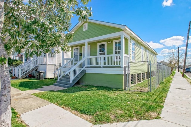 view of front of house featuring a porch, a gate, fence, and a front lawn