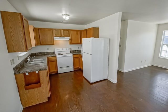 kitchen with white appliances, dark wood finished floors, a sink, dark countertops, and brown cabinets