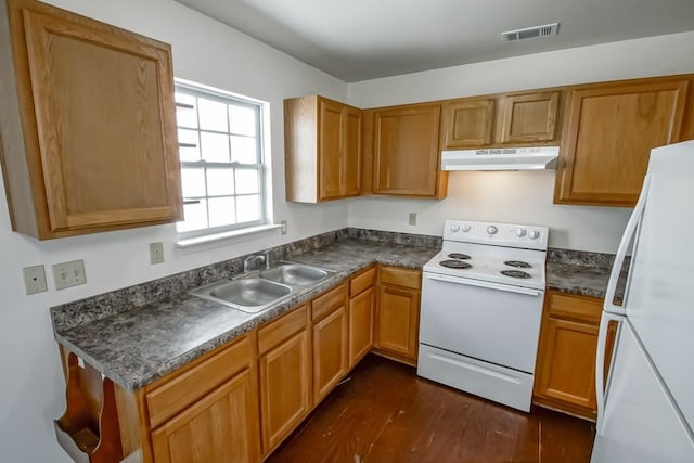 kitchen with white appliances, visible vents, a sink, under cabinet range hood, and dark countertops