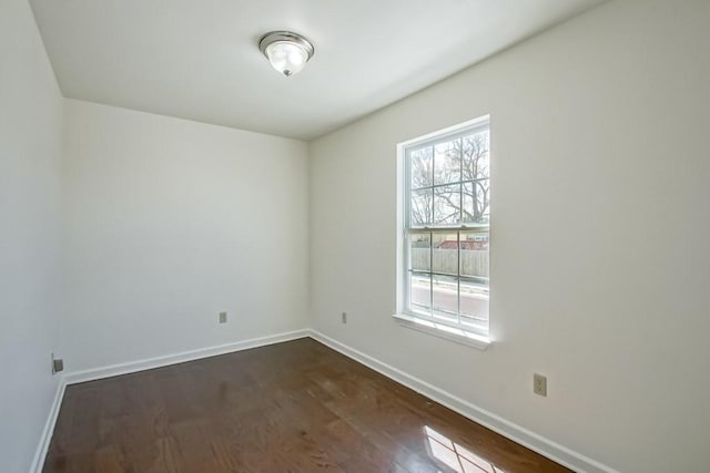 empty room featuring dark wood-style floors and baseboards