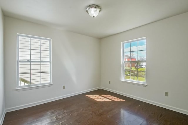 unfurnished room with baseboards and dark wood finished floors