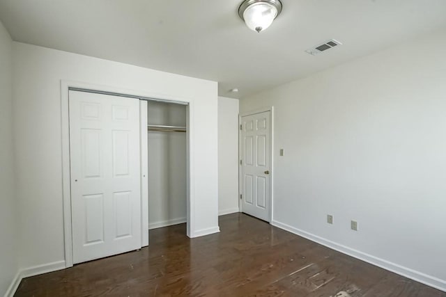 unfurnished bedroom with a closet, visible vents, baseboards, and wood finished floors