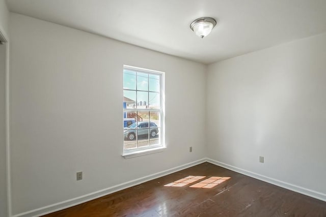 empty room with dark wood-type flooring and baseboards