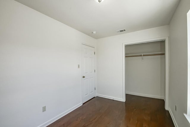 unfurnished bedroom with visible vents, baseboards, a closet, and dark wood-style flooring