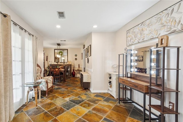 hall with stone tile flooring, visible vents, recessed lighting, and baseboards