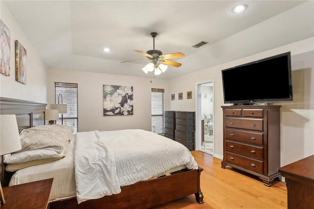 bedroom featuring recessed lighting, visible vents, a tray ceiling, and light wood finished floors