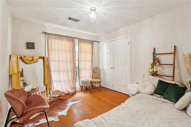 bedroom featuring visible vents, a closet, and wood finished floors