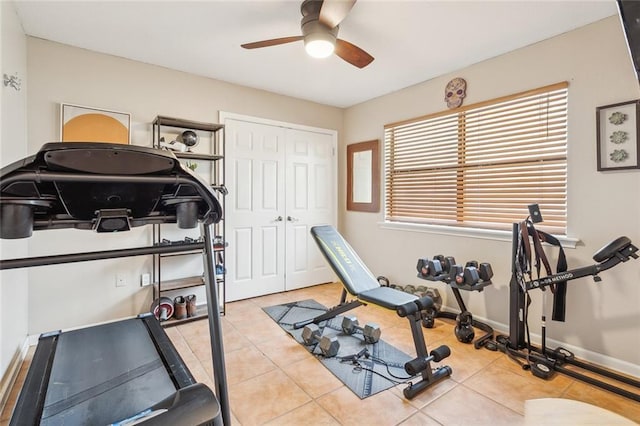 workout room with tile patterned floors, a ceiling fan, and baseboards