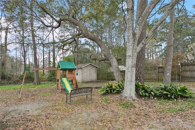 view of yard featuring a storage shed, an outdoor structure, a playground, and fence