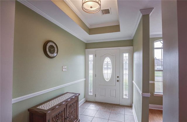 tiled entryway featuring visible vents, a raised ceiling, baseboards, and ornamental molding