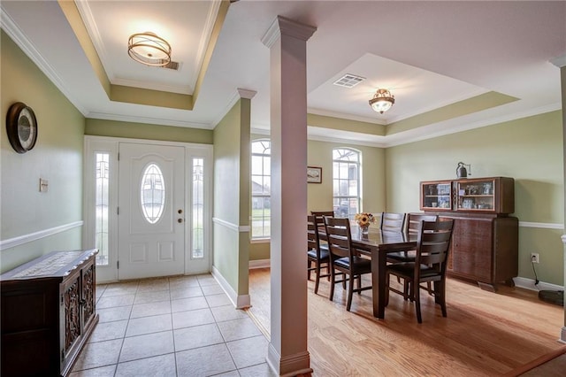 entrance foyer with visible vents, crown molding, a tray ceiling, and decorative columns