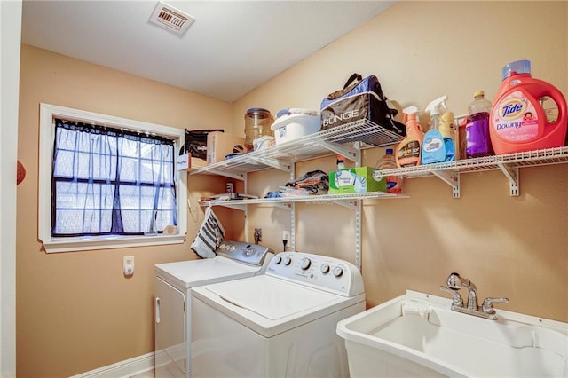 clothes washing area featuring visible vents, baseboards, laundry area, independent washer and dryer, and a sink