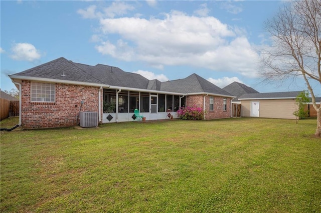 back of house with an outbuilding, a lawn, fence, a sunroom, and brick siding