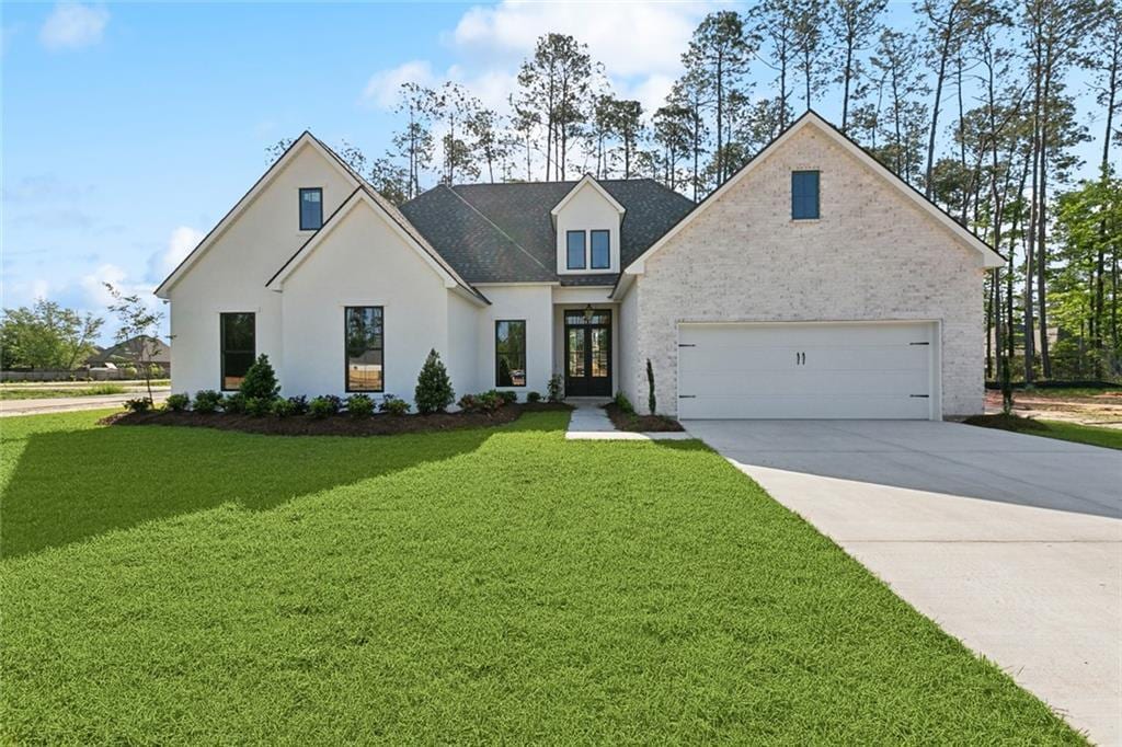 view of front facade with concrete driveway, french doors, and a front yard