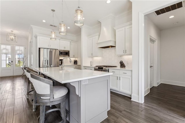 kitchen with tasteful backsplash, visible vents, crown molding, custom range hood, and appliances with stainless steel finishes