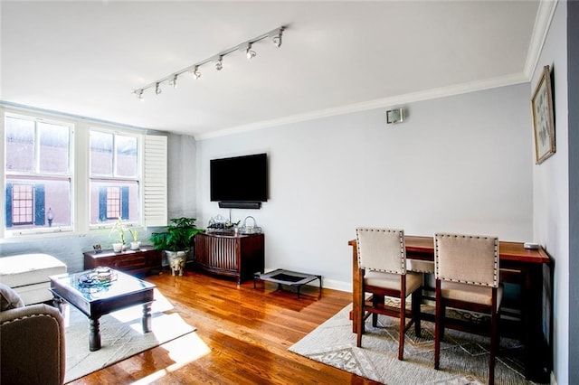 living room featuring crown molding, wood finished floors, baseboards, and track lighting