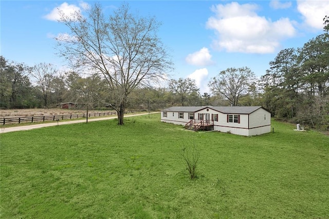 exterior space featuring a rural view, a front lawn, and fence