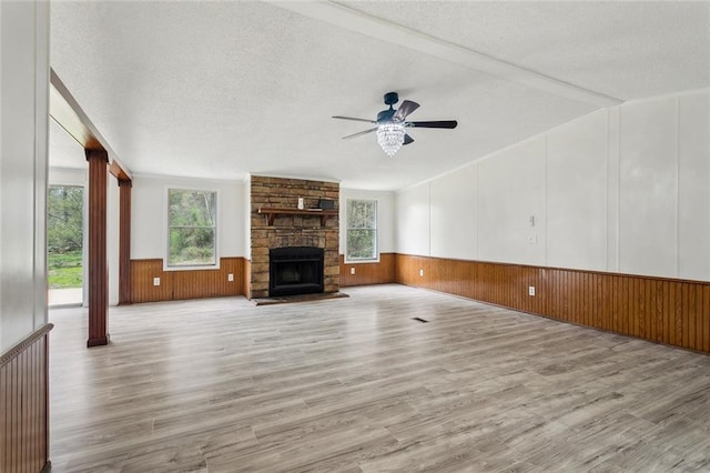 unfurnished living room with plenty of natural light, wainscoting, and a textured ceiling