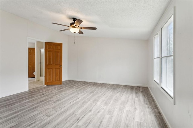 empty room featuring light wood finished floors, a wealth of natural light, and ceiling fan