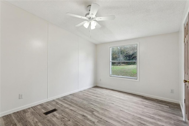 unfurnished room with visible vents, a ceiling fan, a textured ceiling, wood finished floors, and baseboards