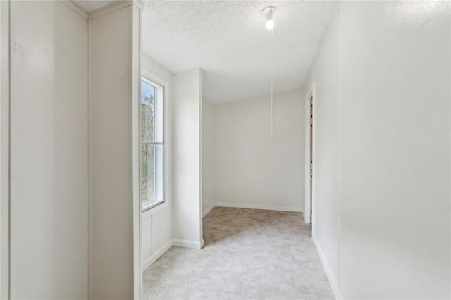 hall featuring plenty of natural light, baseboards, and a textured ceiling