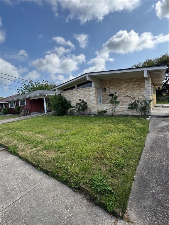 view of front of home with driveway, brick siding, an attached garage, and a front lawn