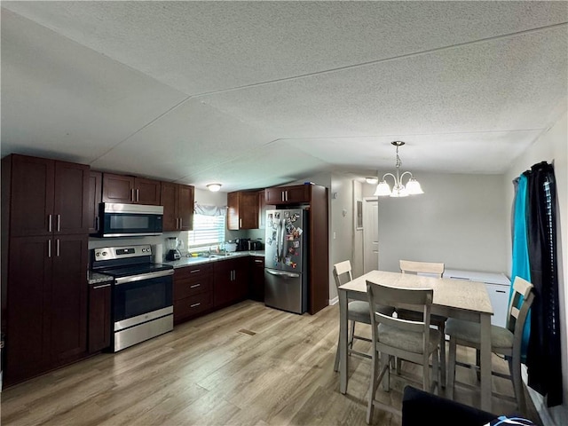 kitchen with appliances with stainless steel finishes, a textured ceiling, lofted ceiling, and light wood-style floors