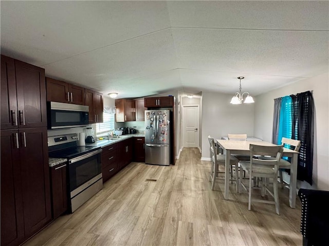 kitchen with a notable chandelier, appliances with stainless steel finishes, light wood finished floors, dark brown cabinets, and hanging light fixtures