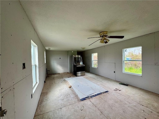 unfurnished living room with a textured ceiling and a ceiling fan