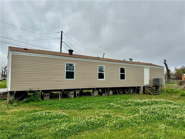 rear view of property with a yard, cooling unit, and entry steps