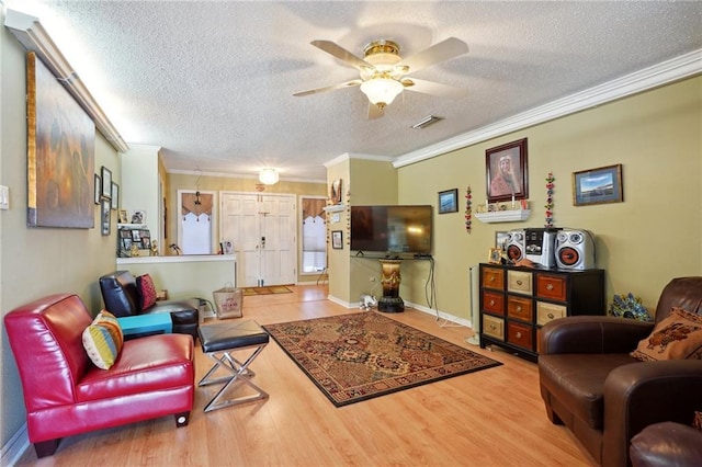 living room with crown molding, ceiling fan, and wood finished floors