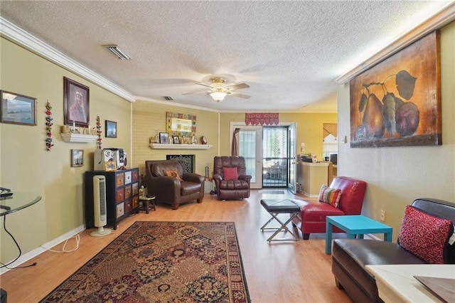 living area with ceiling fan, visible vents, wood finished floors, and ornamental molding