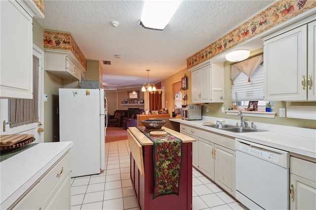 kitchen with light countertops, a notable chandelier, white appliances, a textured ceiling, and a sink