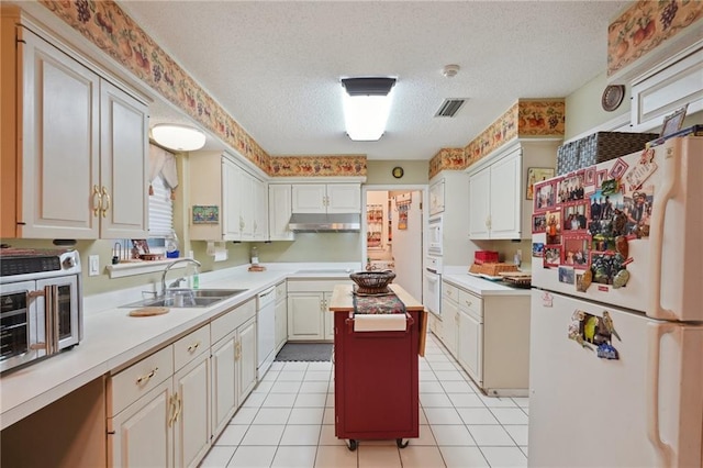 kitchen featuring white appliances, visible vents, a sink, light countertops, and under cabinet range hood