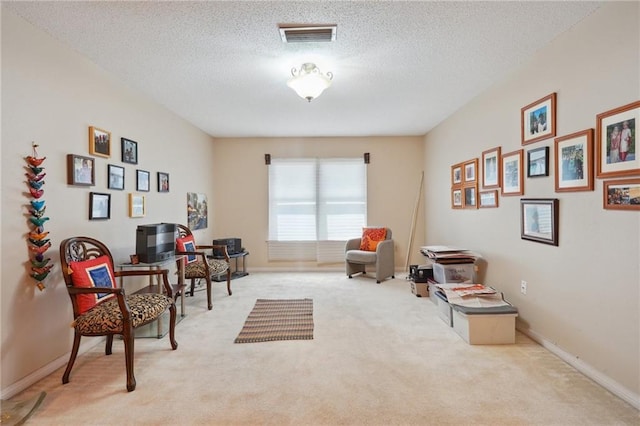 sitting room with visible vents, baseboards, a textured ceiling, and carpet flooring