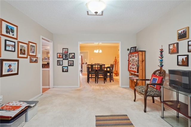 interior space with a chandelier, light colored carpet, a textured ceiling, and baseboards