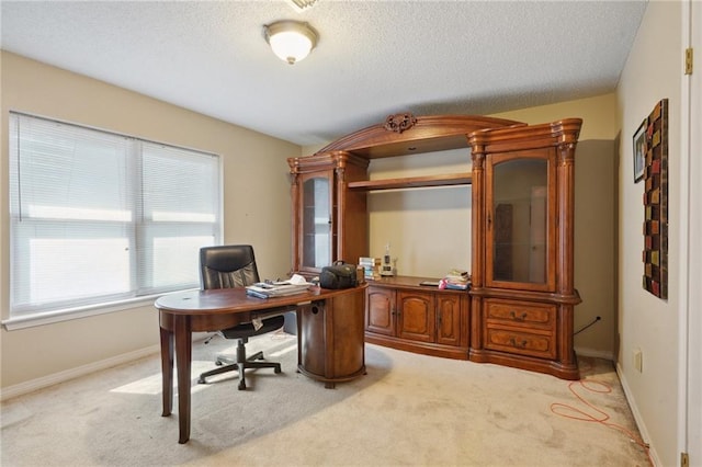 office area featuring baseboards, light colored carpet, and a textured ceiling